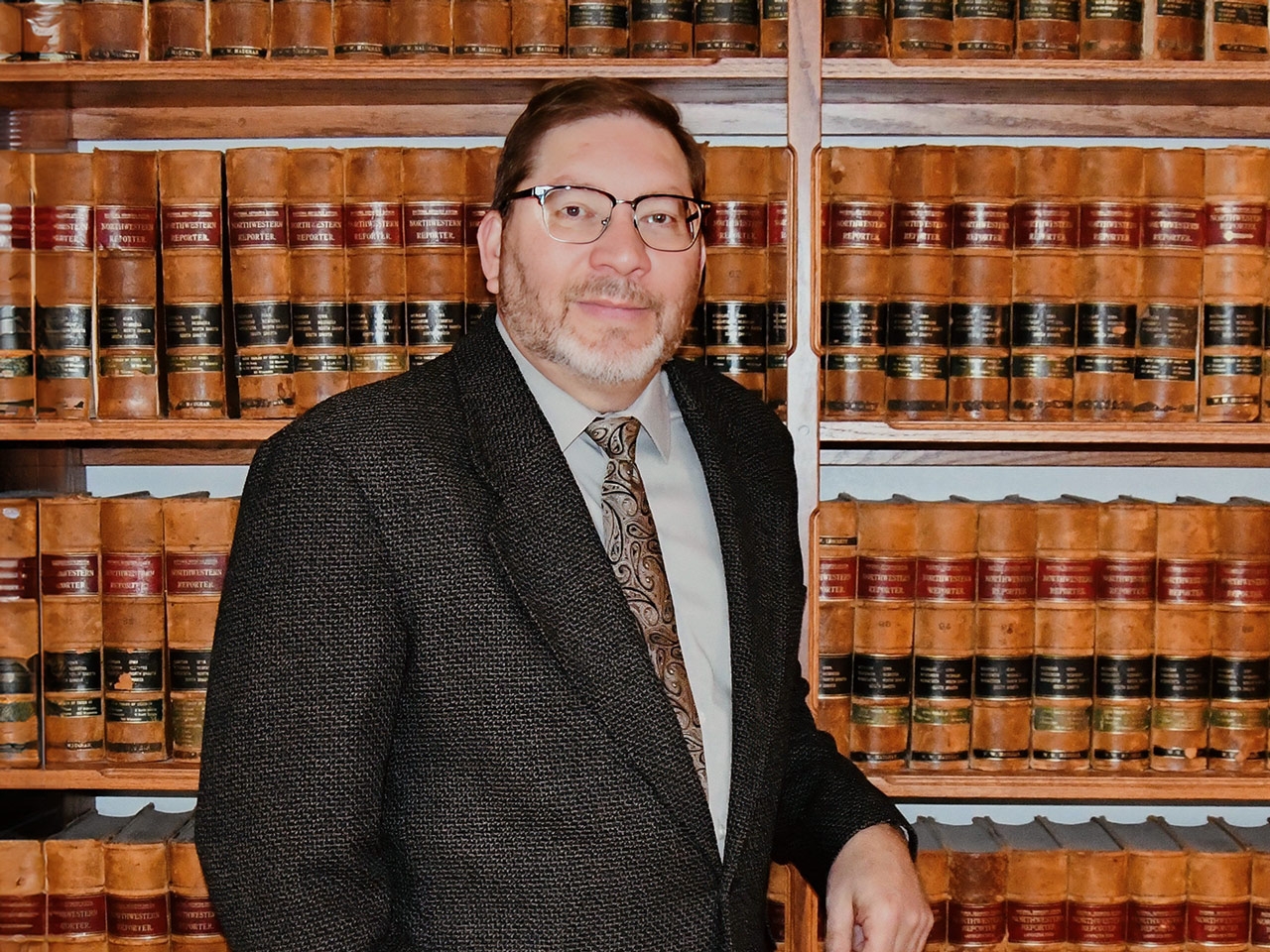 Brian D. Jones leaning on a bookshelf