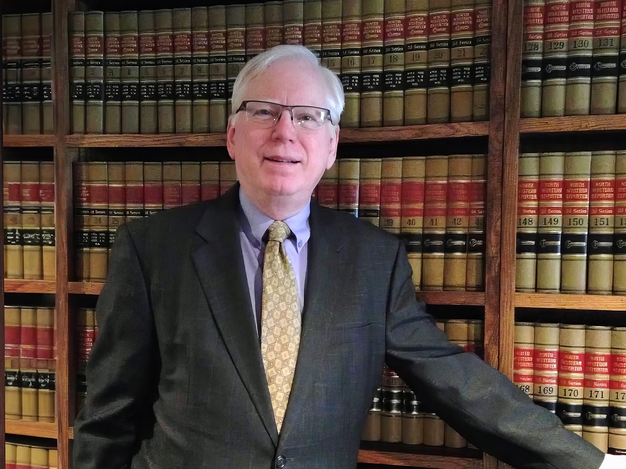 Steven R. Bakke leaning on a bookshelf